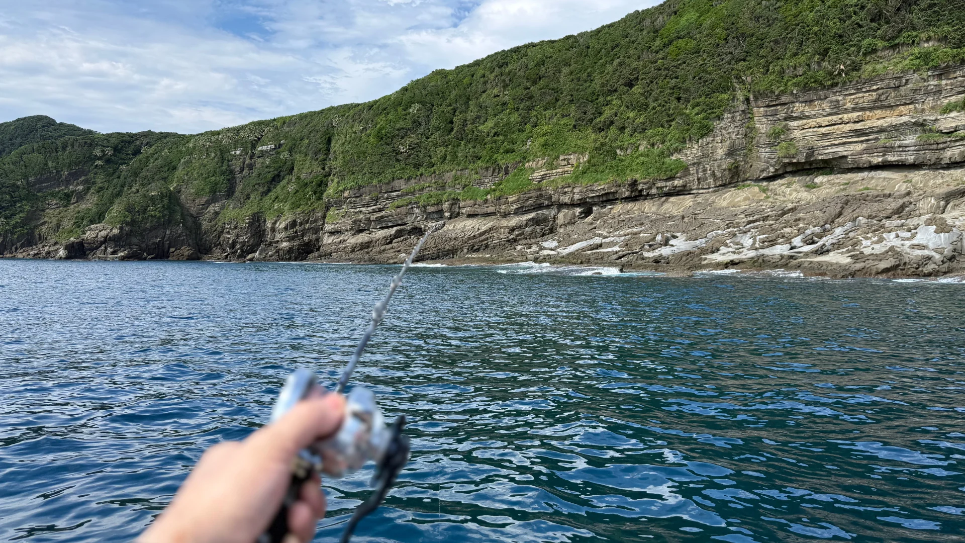 岩場の近くで船から釣りを楽しむ様子
